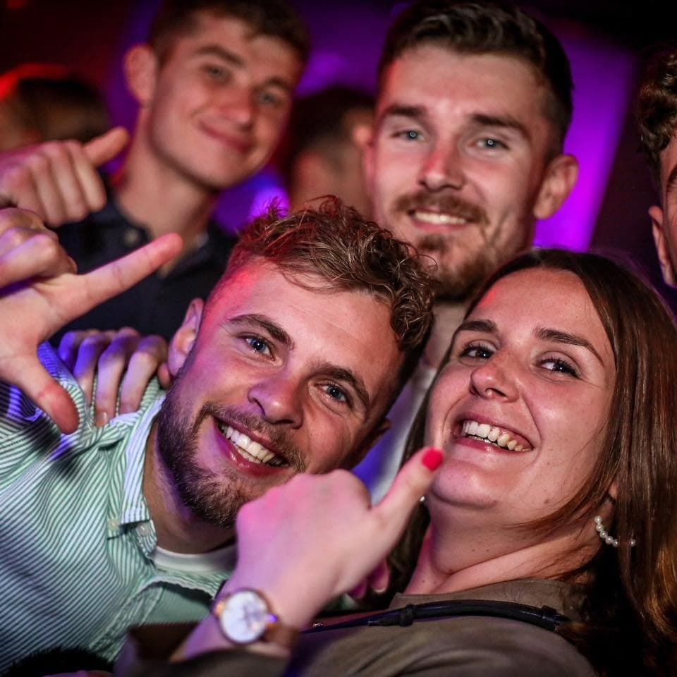 Un groupe d’amis dans la lumière magenta de la salle